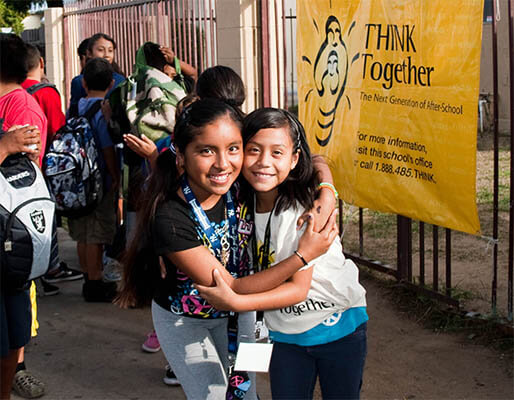 Two schoolgirls smiling at camera at a Think Together event