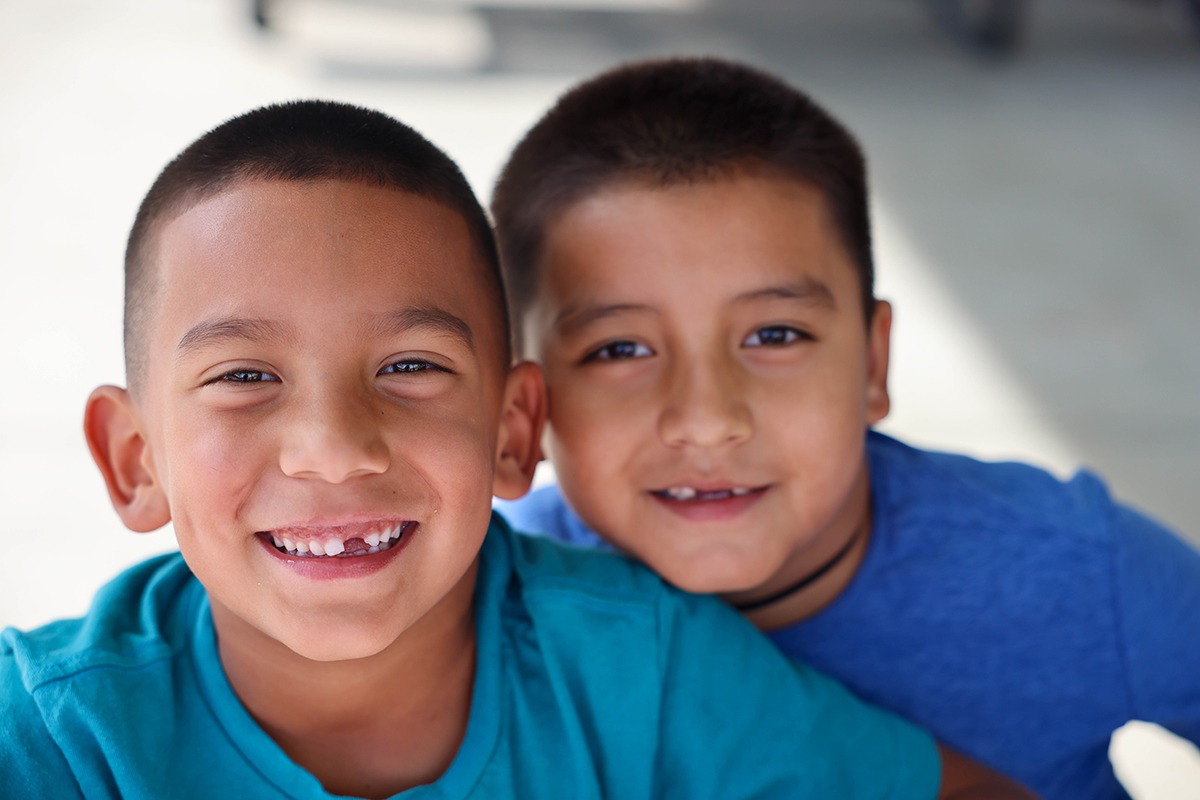 two boys in blue shirts smiling